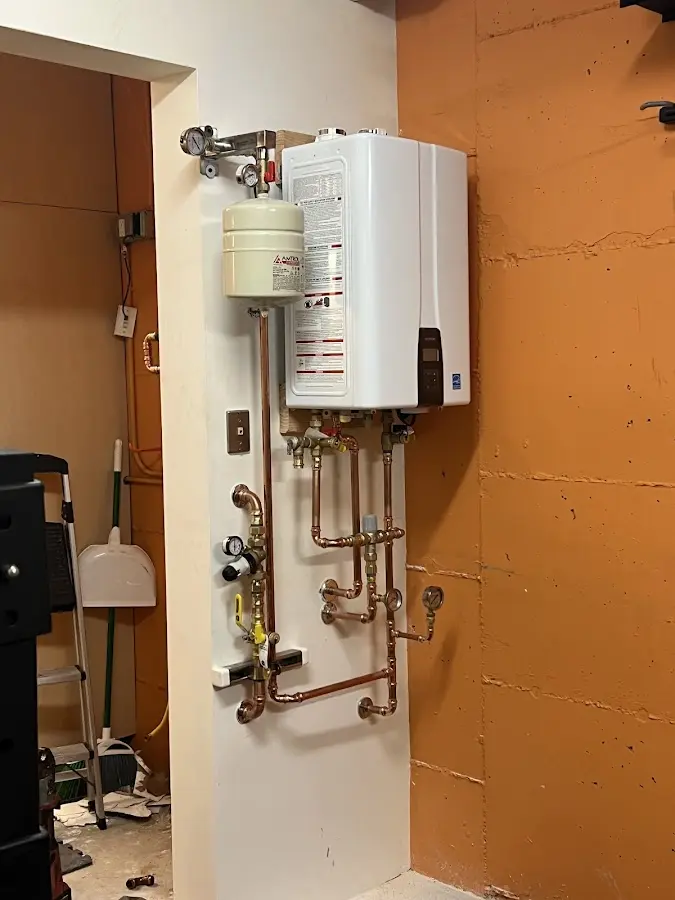 Plumbing technician inspecting water heater connections in North Logan